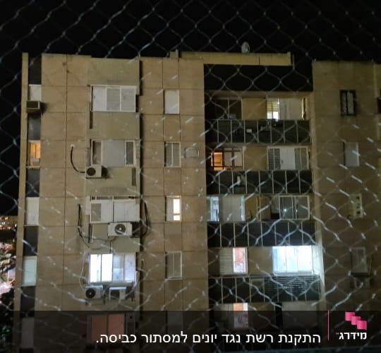 רשת מתכת מול בניין מגורים בלילה